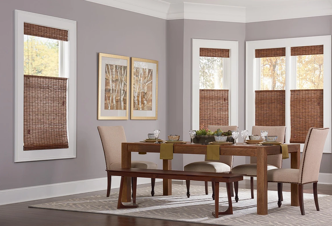 A dining room with brown woven wood shades and a table