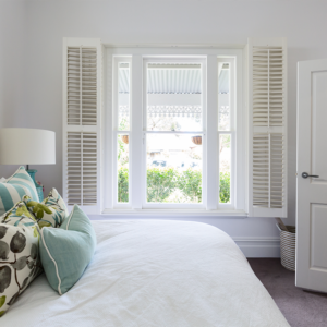 A bedroom with a bed and a window with shutters