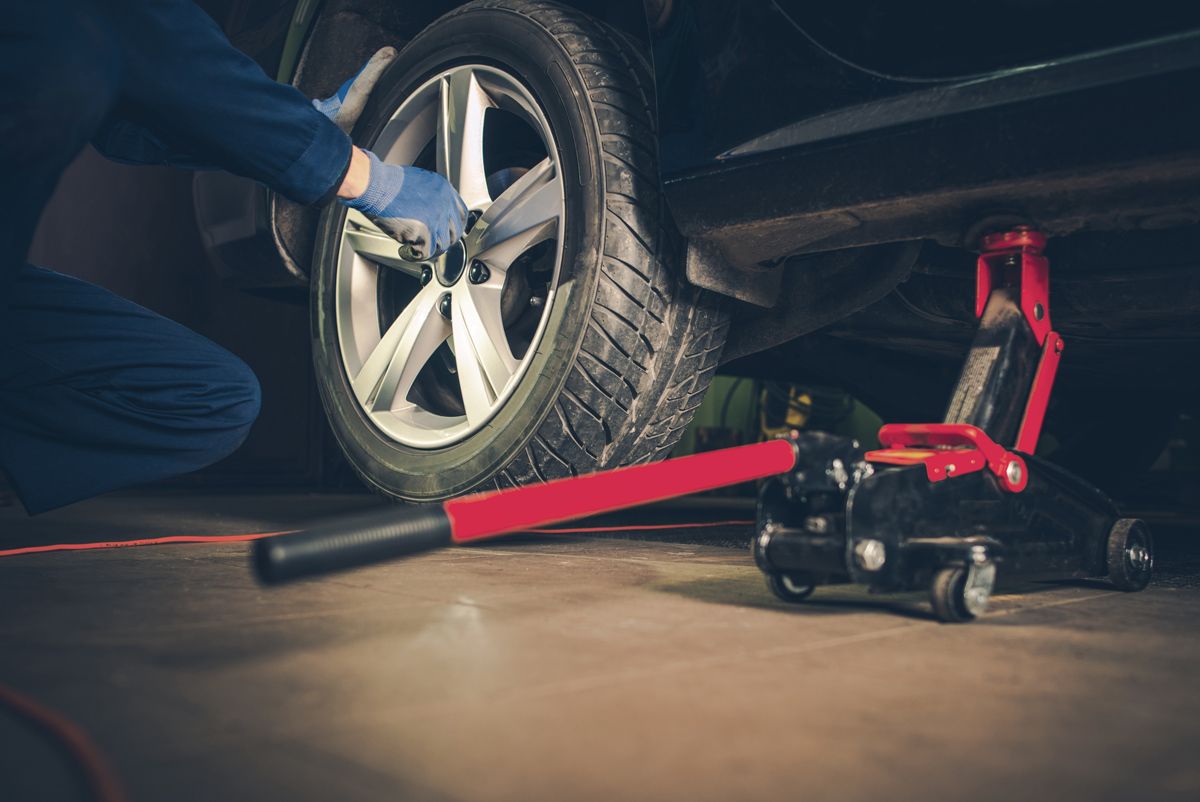 car on jack tire service | Ten-Four Auto