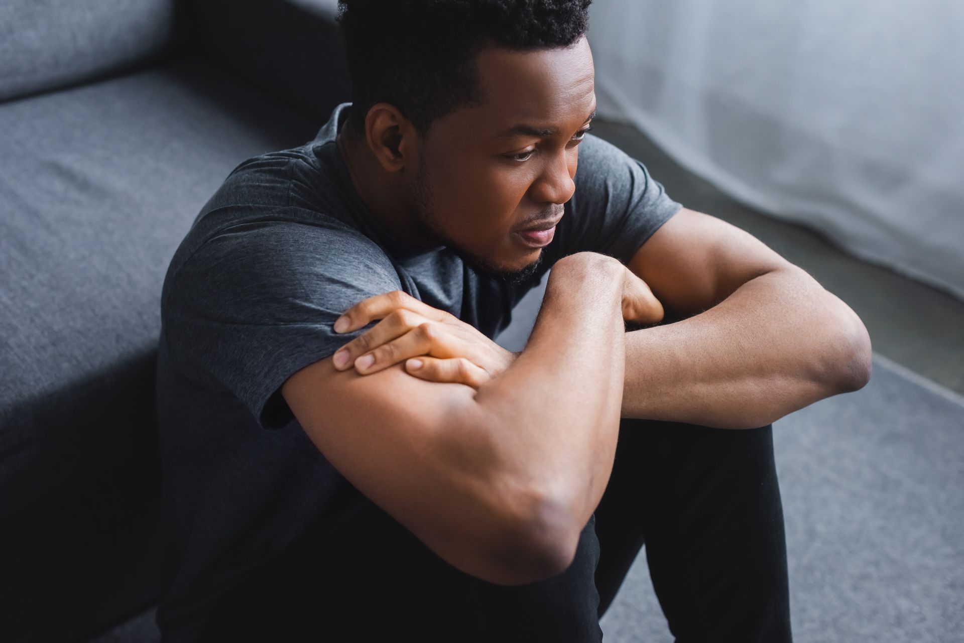 A man is sitting on the floor with his arms crossed.