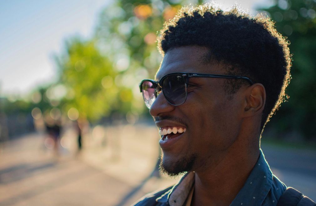 A close up of a man wearing sunglasses and smiling.