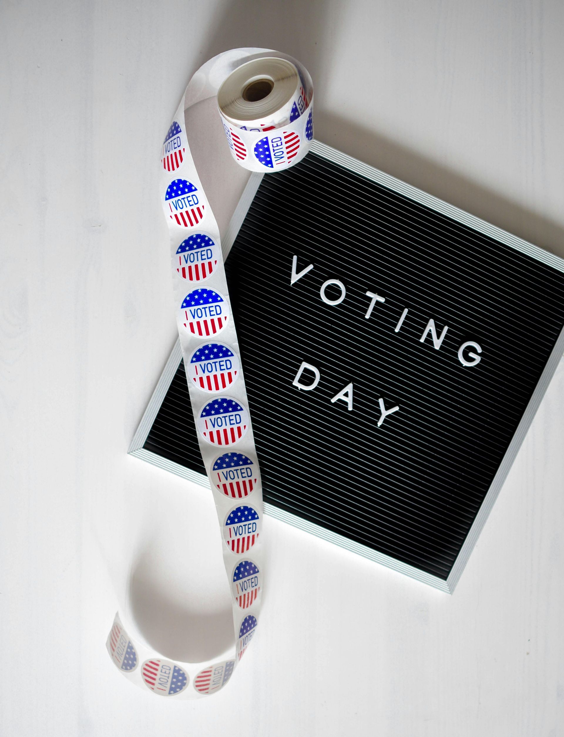 A roll of voting stickers is sitting next to a sign that says voting day.