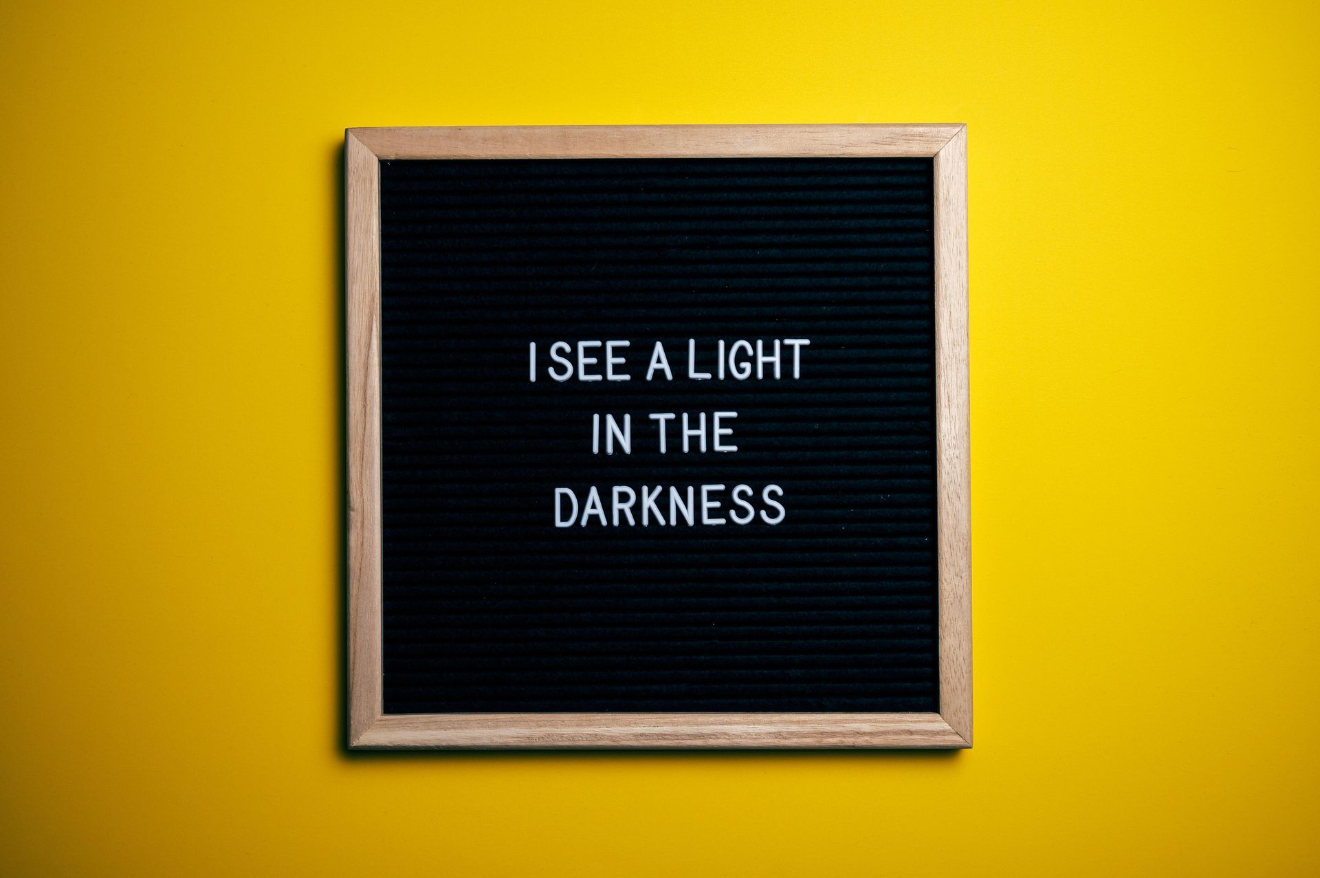 A black letter board with the words `` i see a light in the darkness '' written on it.