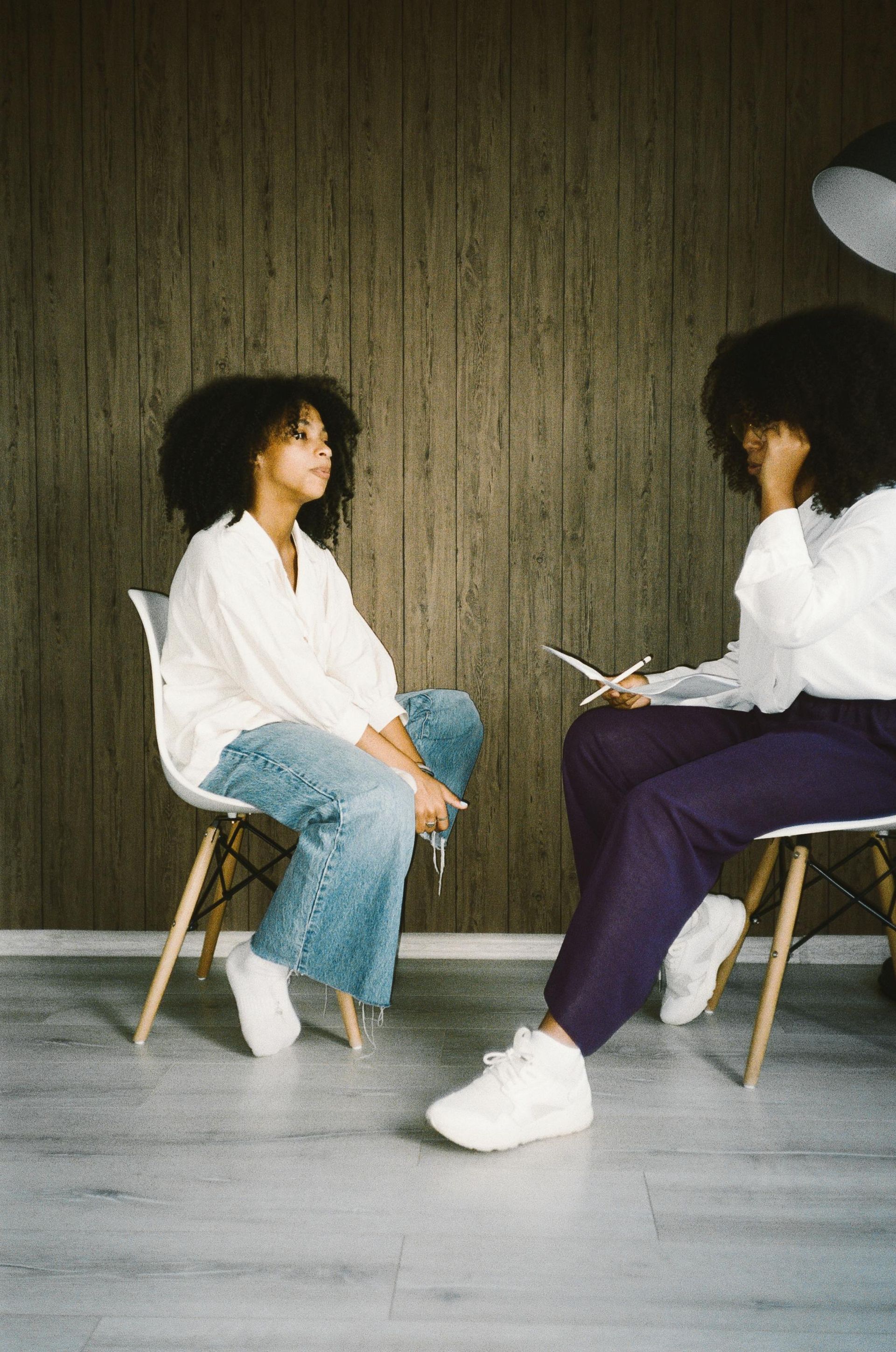 Two women are sitting in chairs talking to each other.