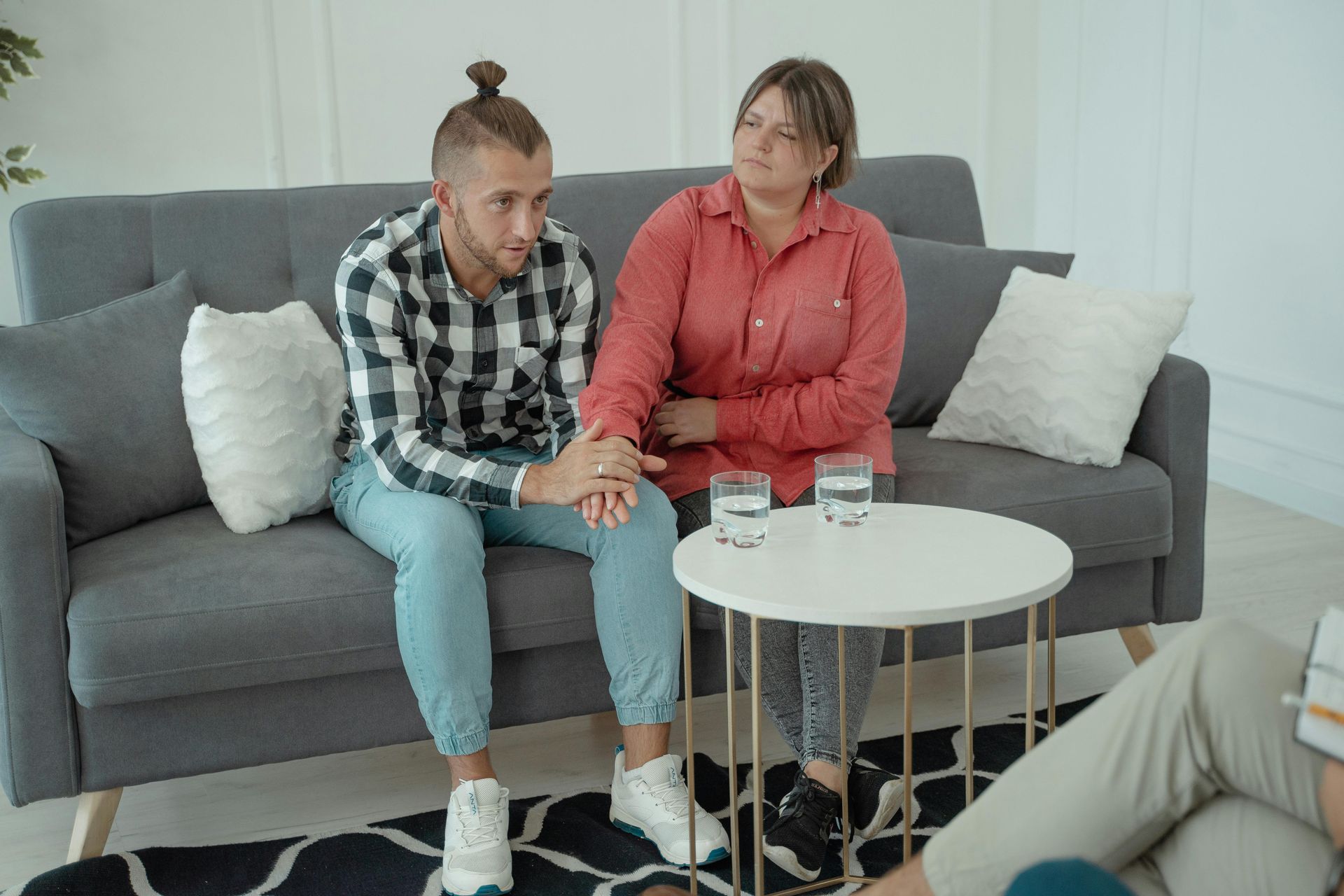 A man and a woman are sitting on a couch talking to each other.