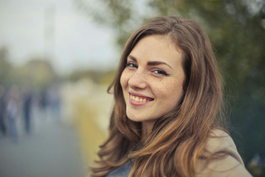 A woman with long hair and freckles is smiling for the camera.