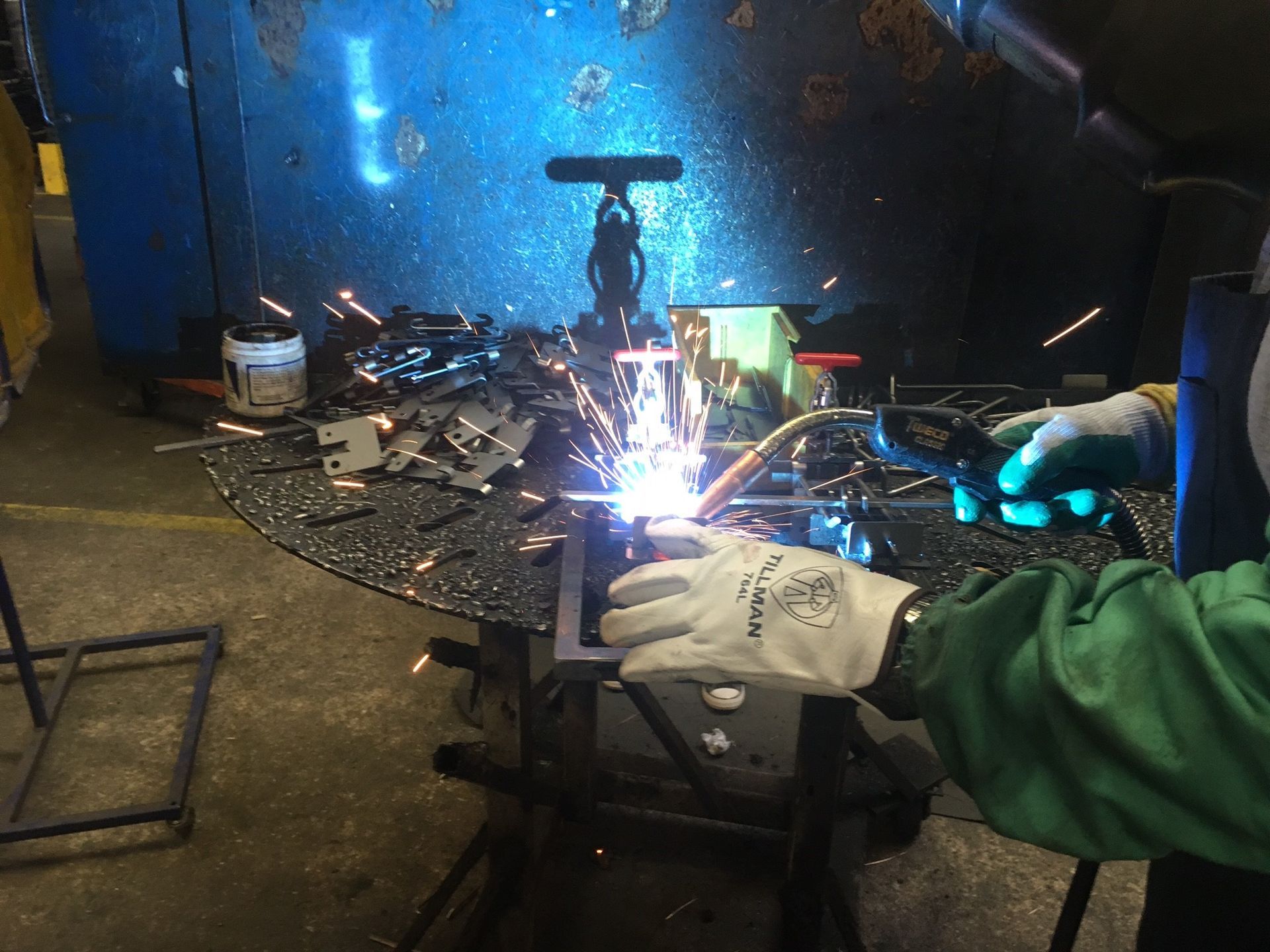 A person wearing gloves is welding a piece of metal.