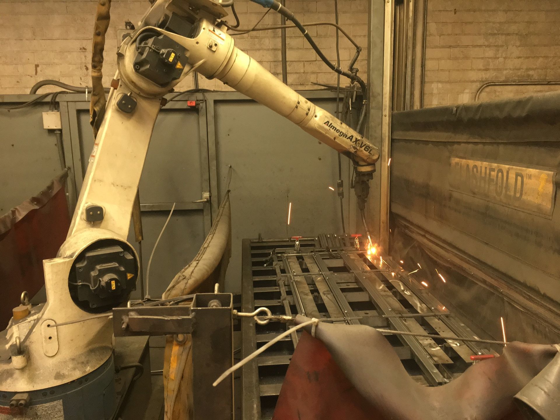 A robotic arm is welding a piece of metal in a factory