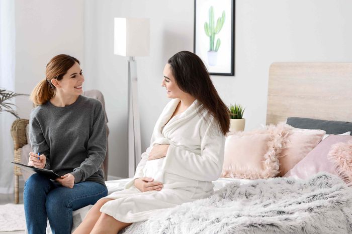 Pregnant woman sitting on bed with her doula