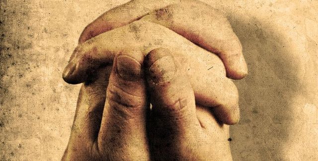 A person is praying with their hands folded in prayer.