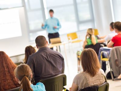 A group of people are sitting in a classroom listening to a lecture.