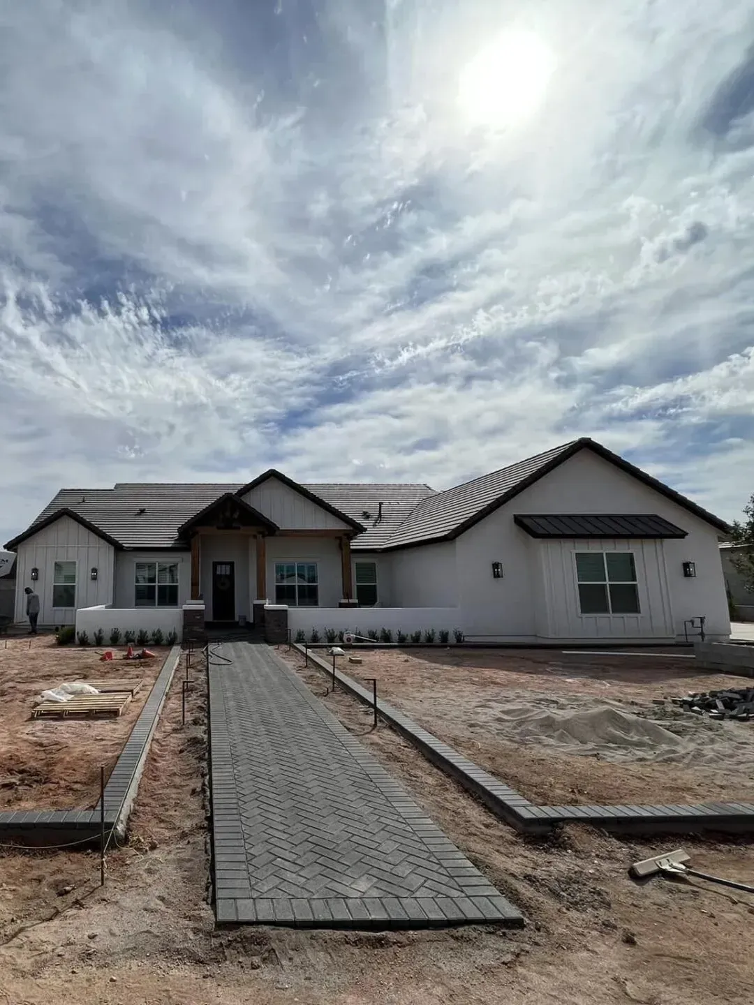 Modern white house with a brick pathway and cloudy sky. Queen Creek Arizona