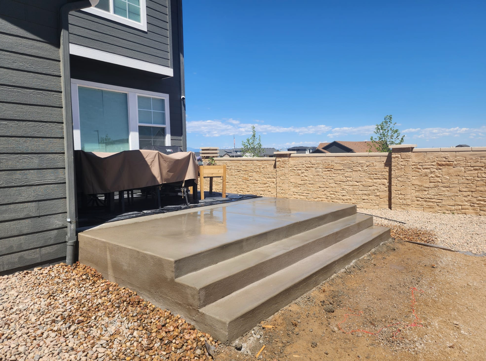 A concrete deck with stairs leading up to it is being built in front of a house.