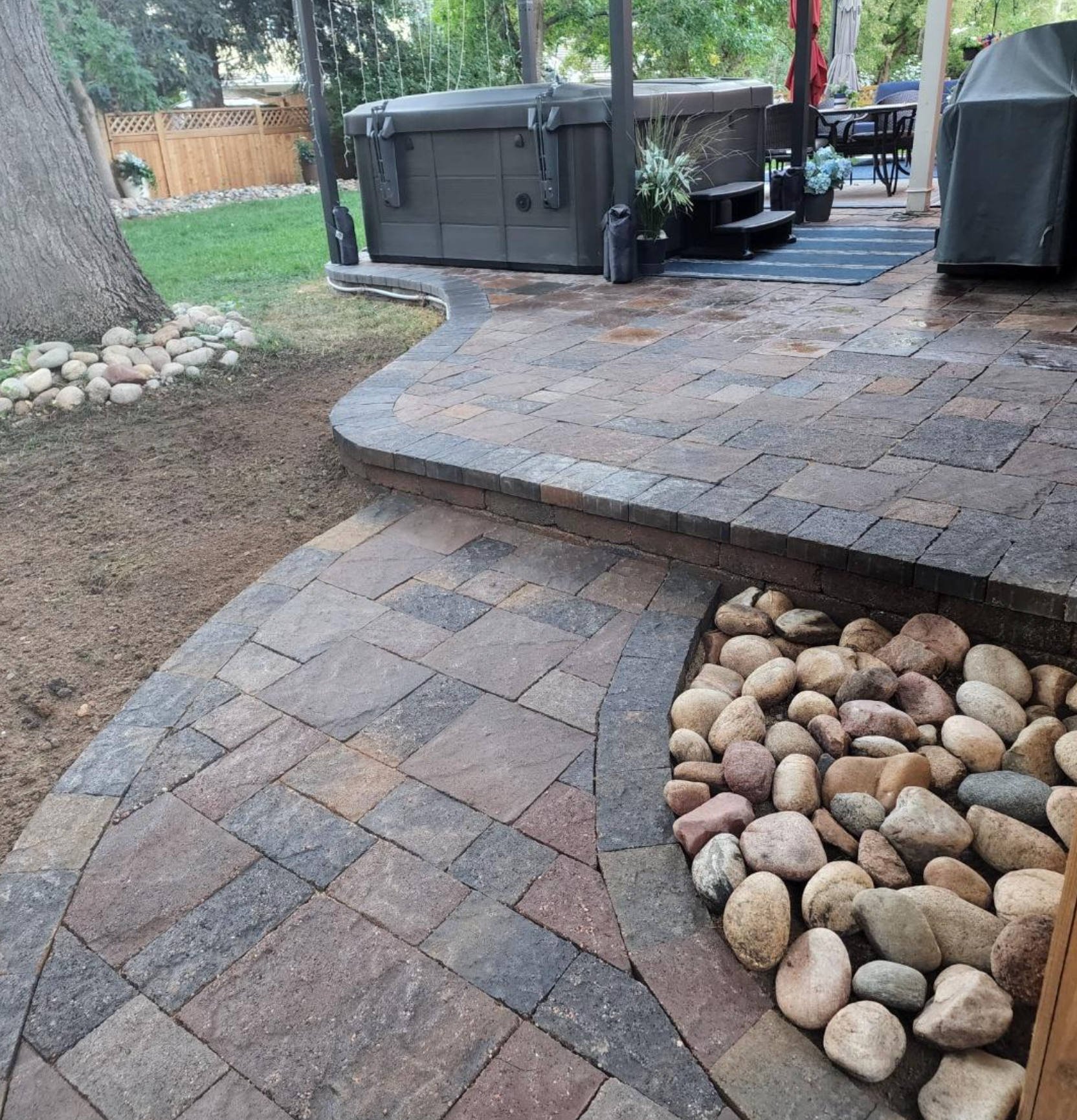A patio with a hot tub in the background and rocks in the middle