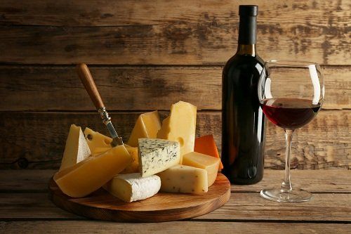 un tagliere di formaggi,una bottiglia e un bicchiere di vino rosso