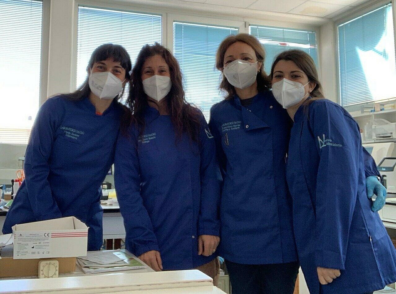 Un gruppo di donne che indossano maschere e cappotti blu posano per una foto.
