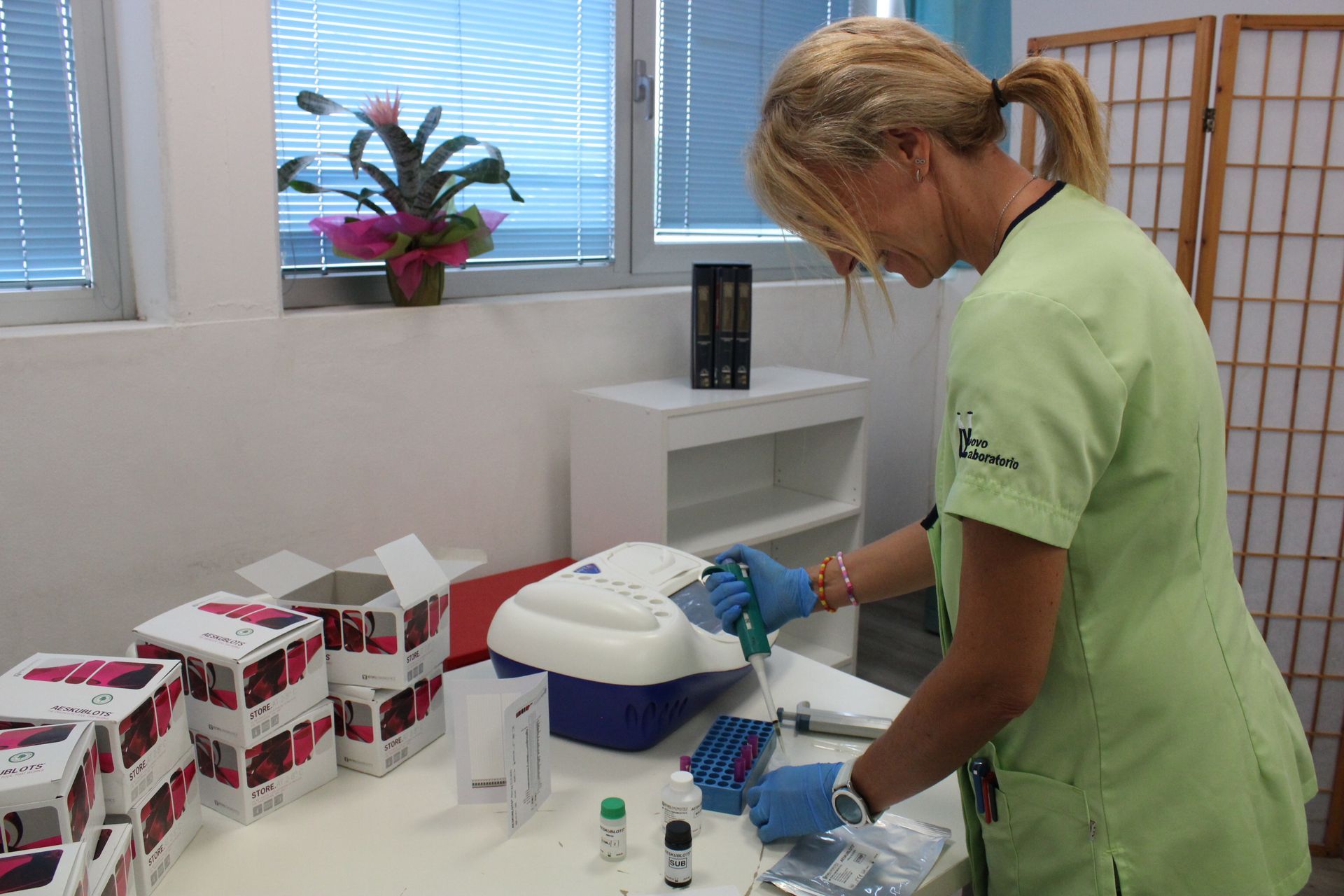 Una donna con un camice verde lavora in un laboratorio.