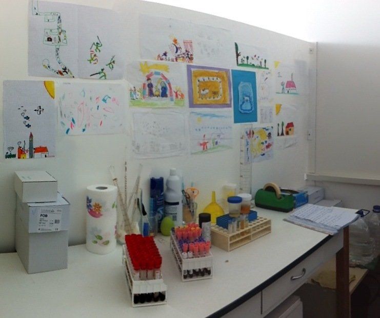 Una scrivania con un mucchio di oggetti sopra e disegni sul muro