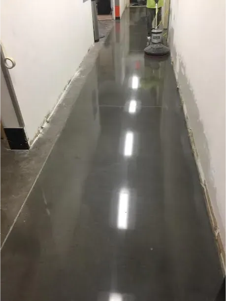 A long hallway with a shiny concrete floor and a vacuum cleaner.