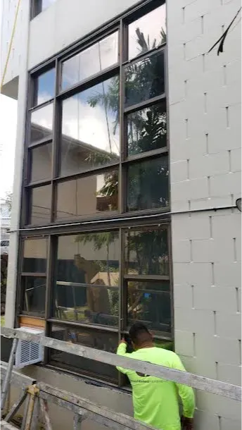 A man is installing a window on the side of a building.