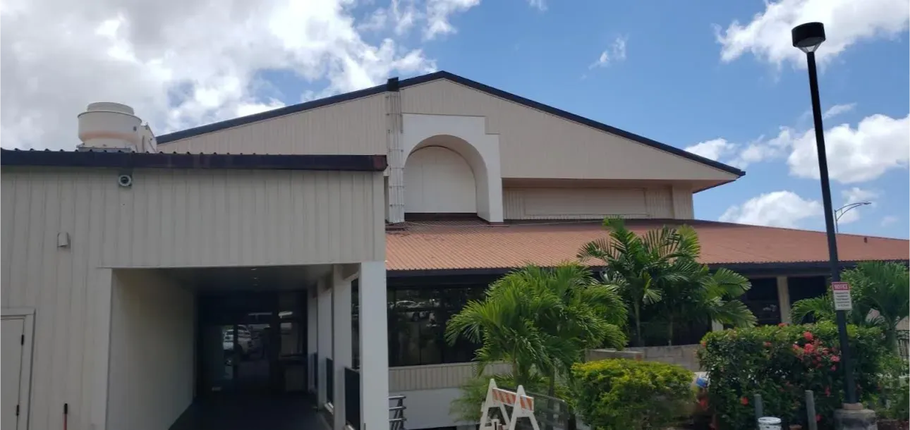 A large white building with a red roof and a parking lot in front of it.