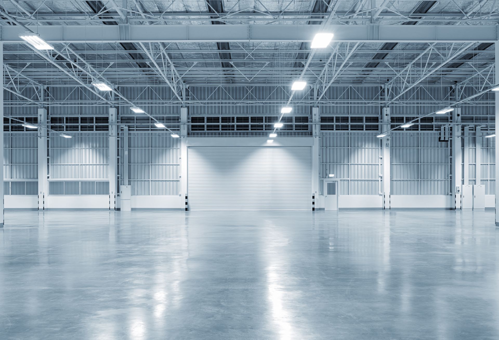 An empty warehouse with a concrete floor and a roller door.