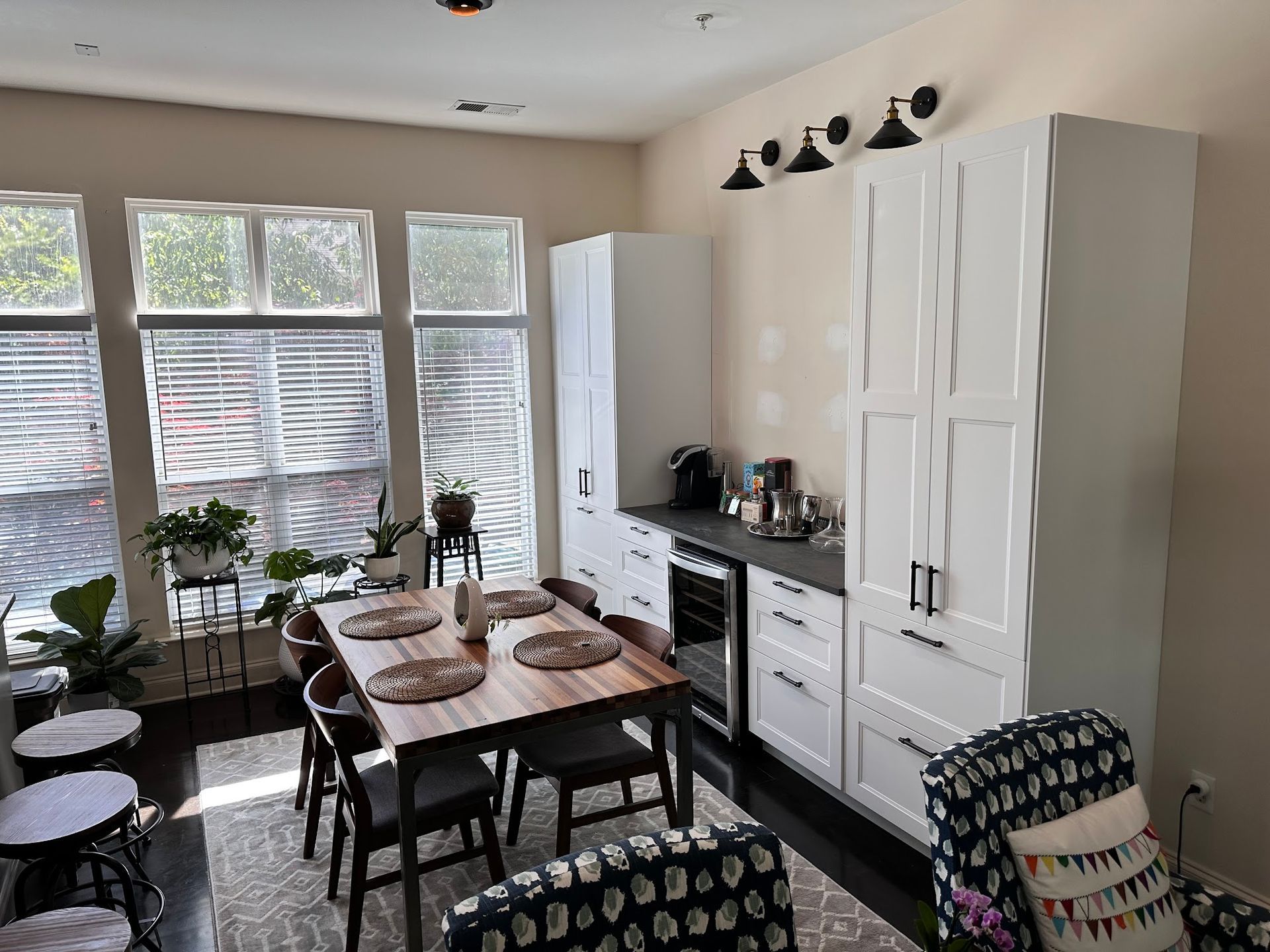 A kitchen with a wooden table and chairs and white cabinets.