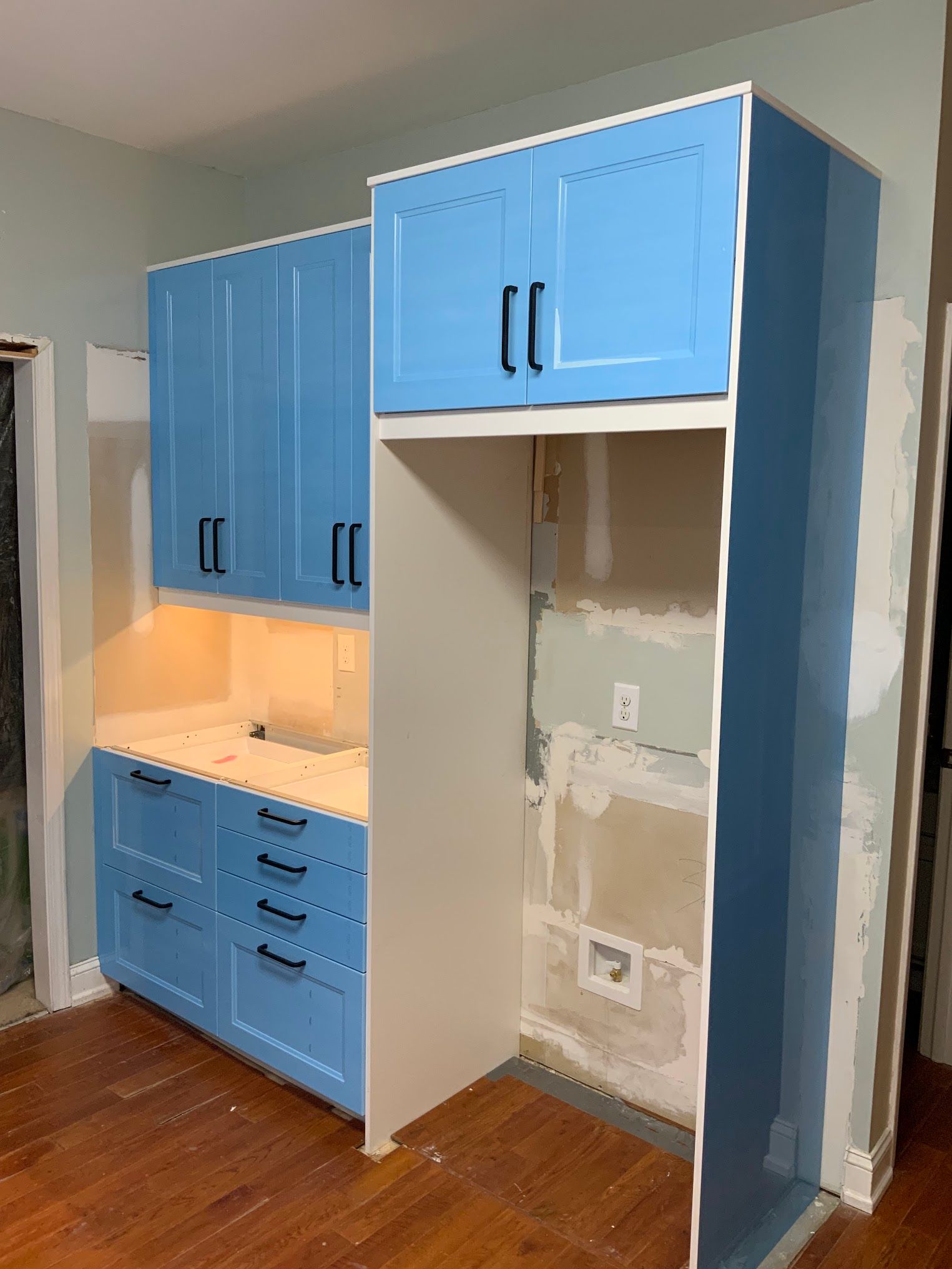 A kitchen with blue cabinets and white counter tops is being remodeled.