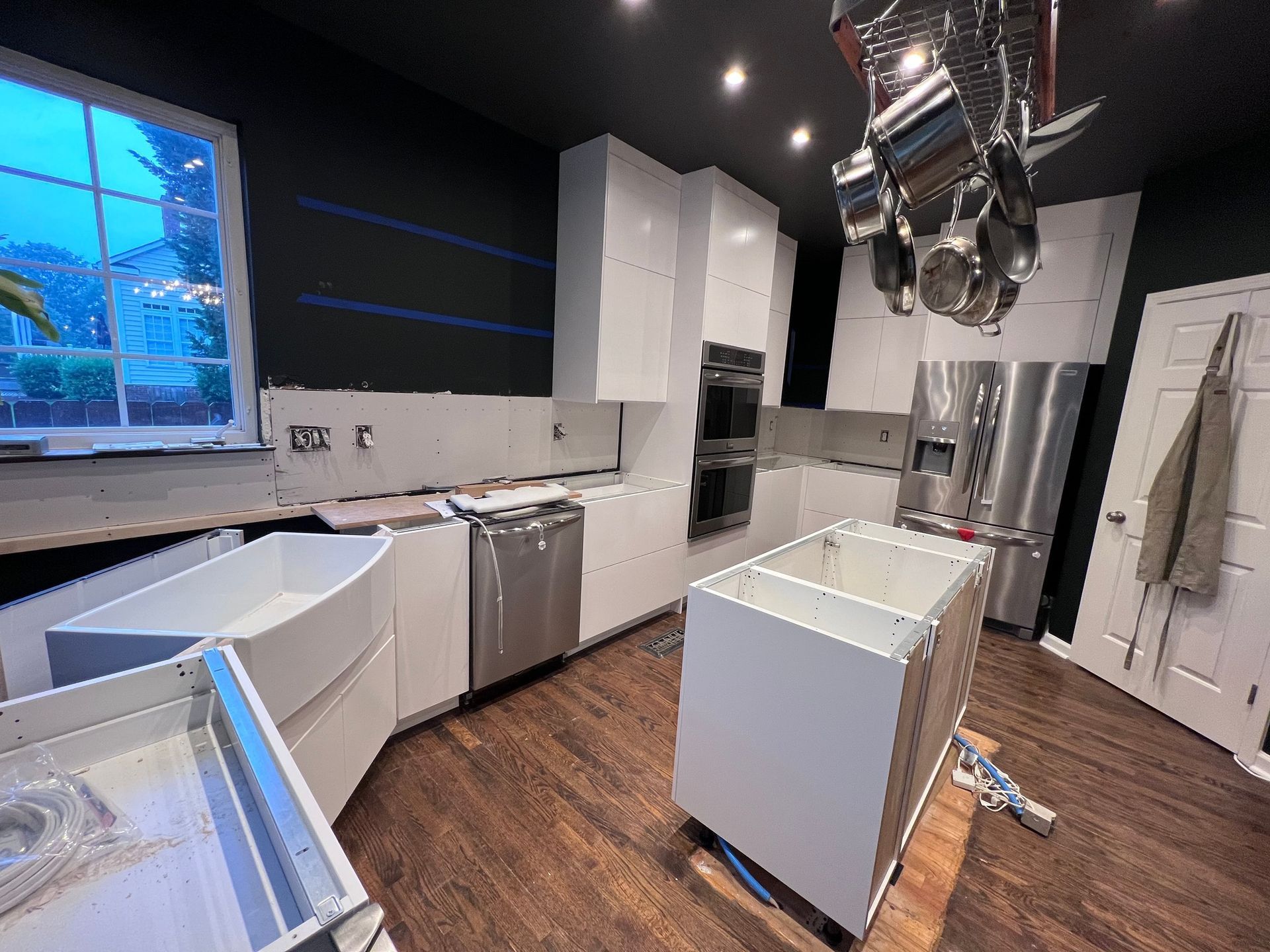 A kitchen under construction with stainless steel appliances and white cabinets.