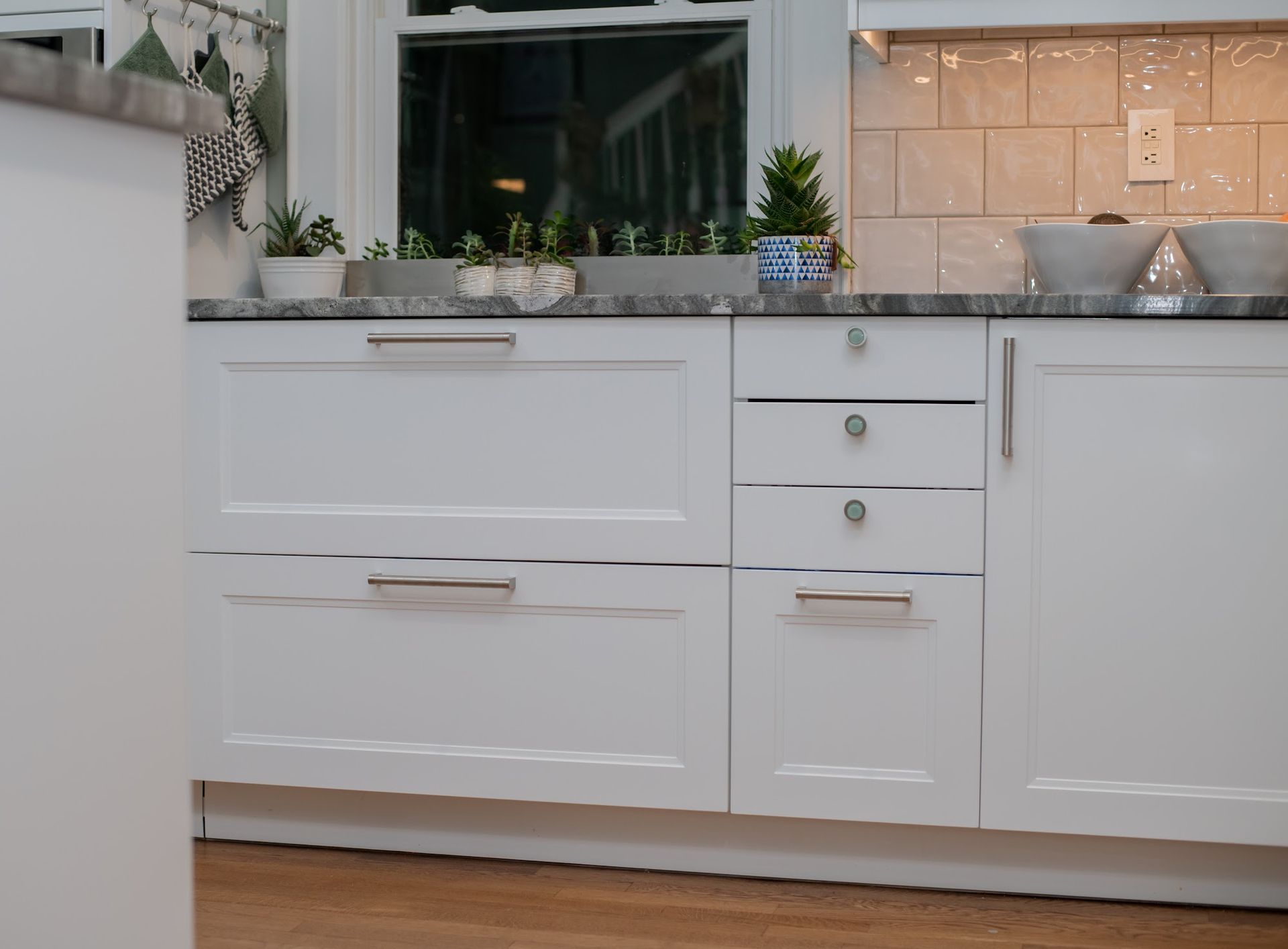A kitchen with white cabinets and a marble counter top