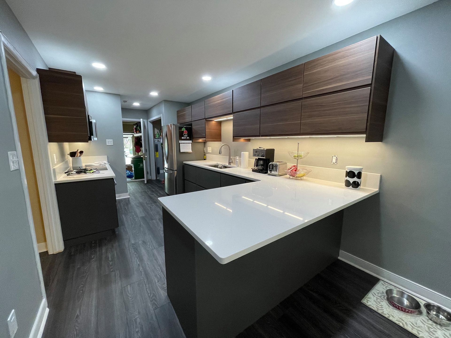 A kitchen with white counter tops and wooden cabinets