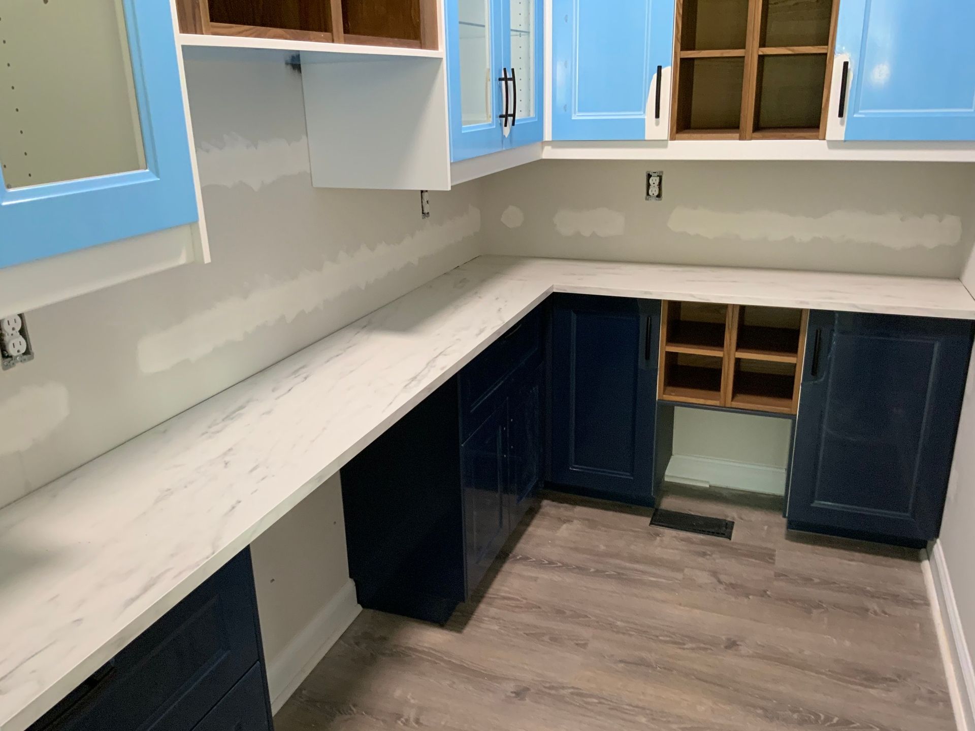 A kitchen with blue cabinets and white counter tops.
