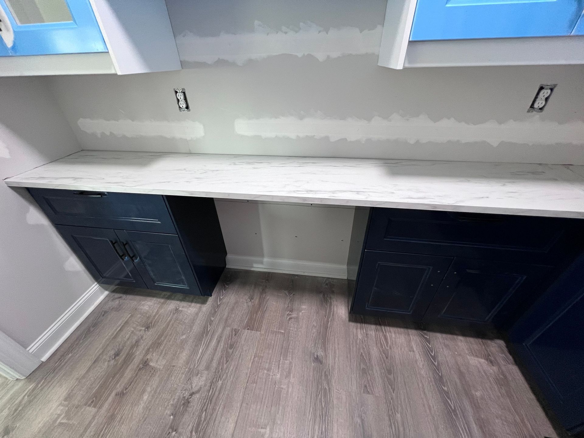 A kitchen with blue cabinets and a white counter top.