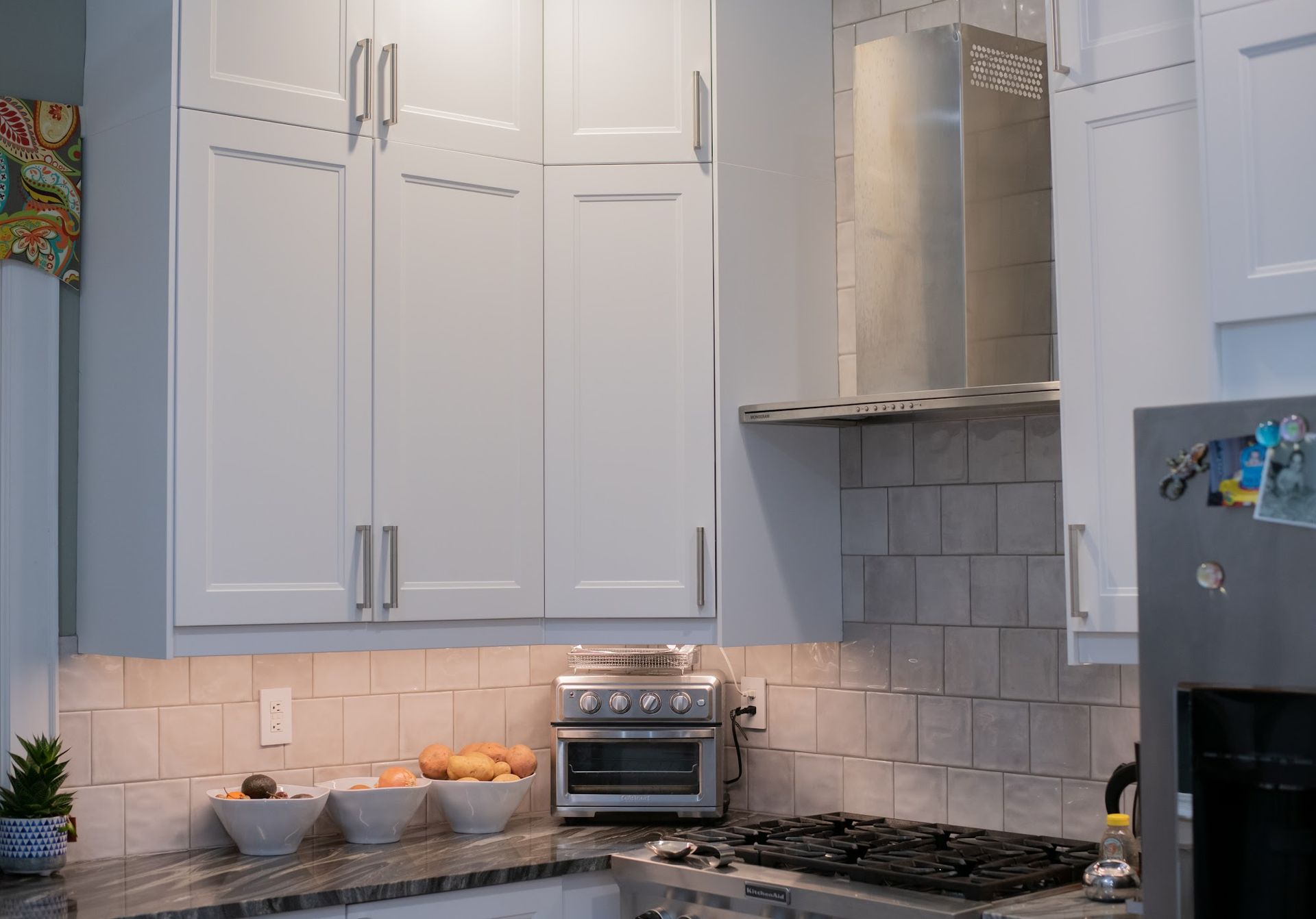 A kitchen with white cabinets and a stove top oven