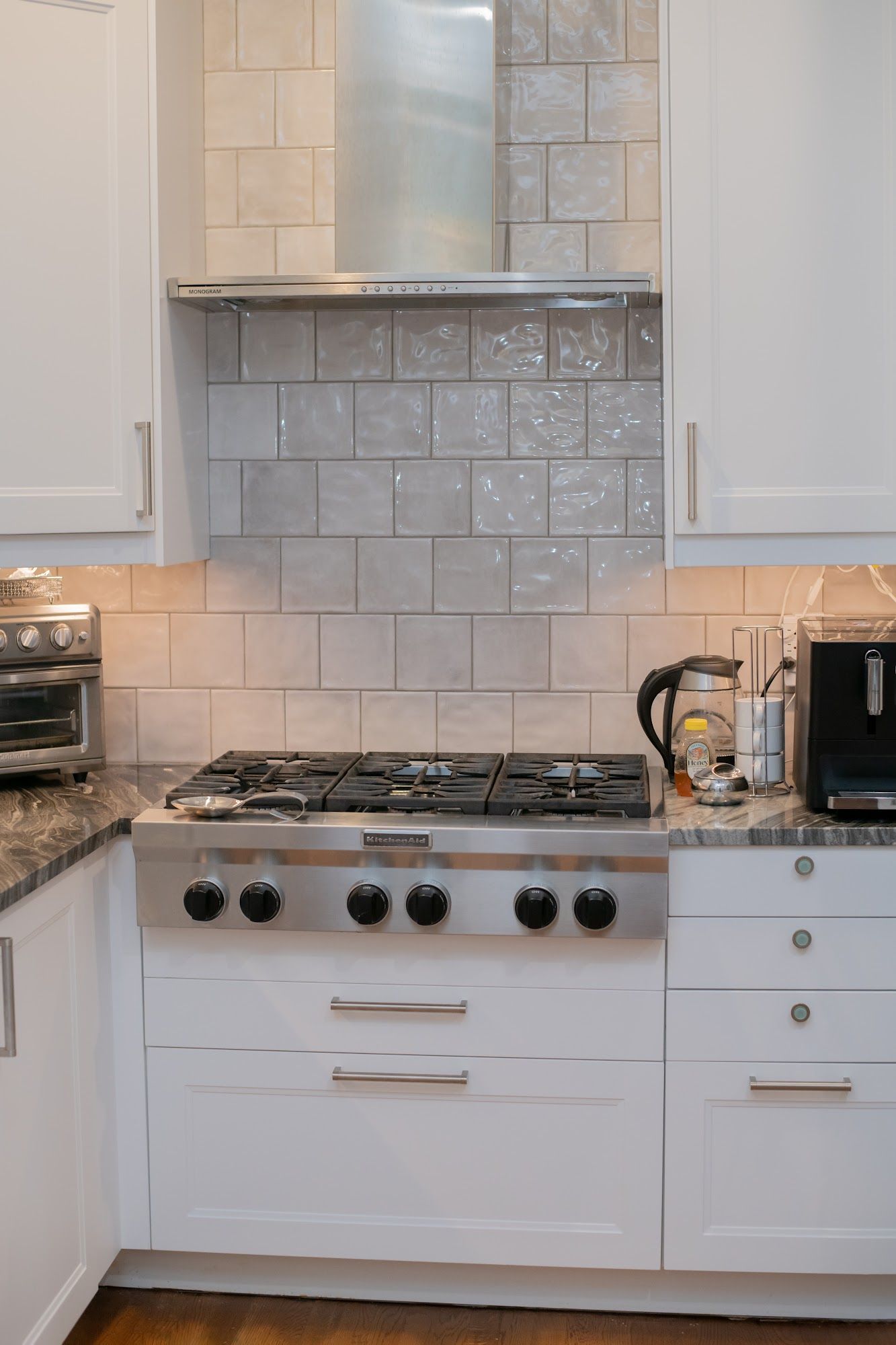 A kitchen with white cabinets and a stove top oven.