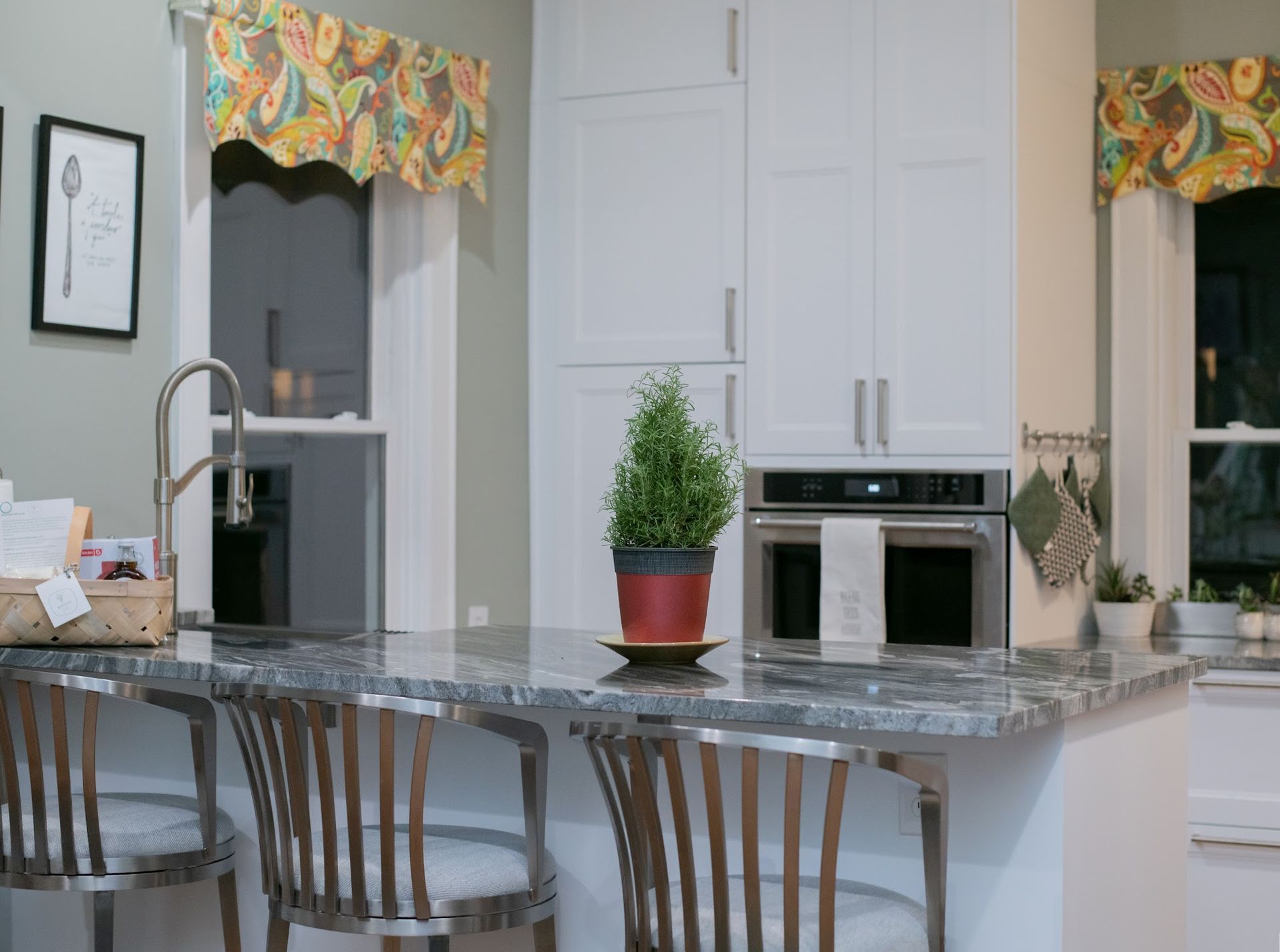 A kitchen with white cabinets , granite counter tops , stainless steel appliances and a potted plant on the counter.