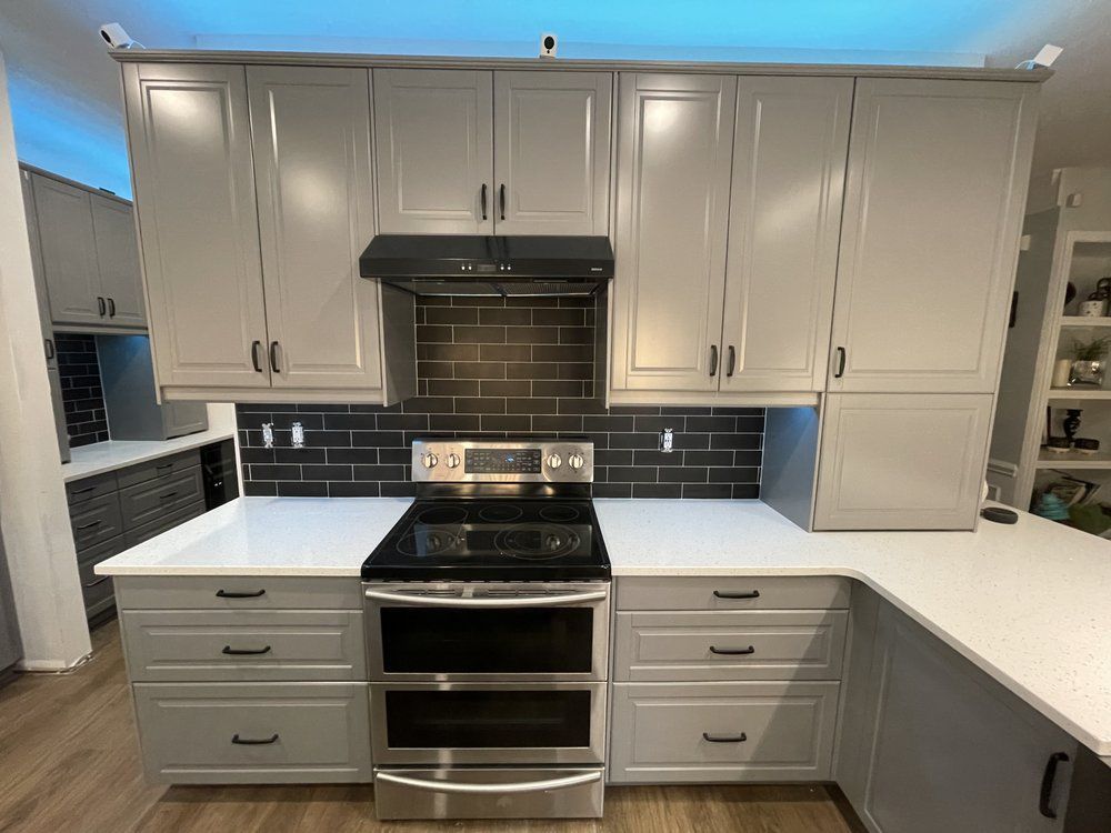 A kitchen with white cabinets , stainless steel appliances , and a black stove top oven.