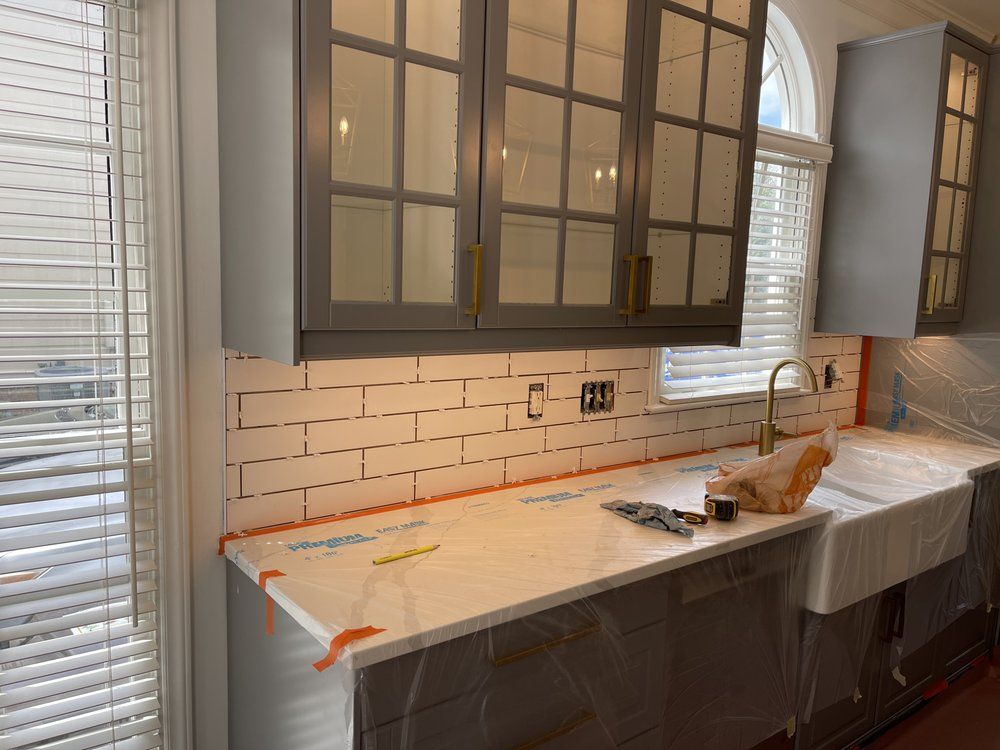 A kitchen with gray cabinets and white counter tops is being remodeled.