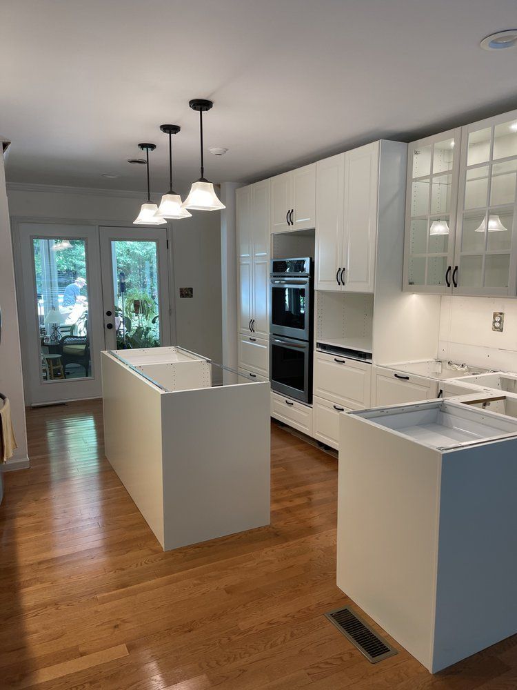 A kitchen with white cabinets and hardwood floors