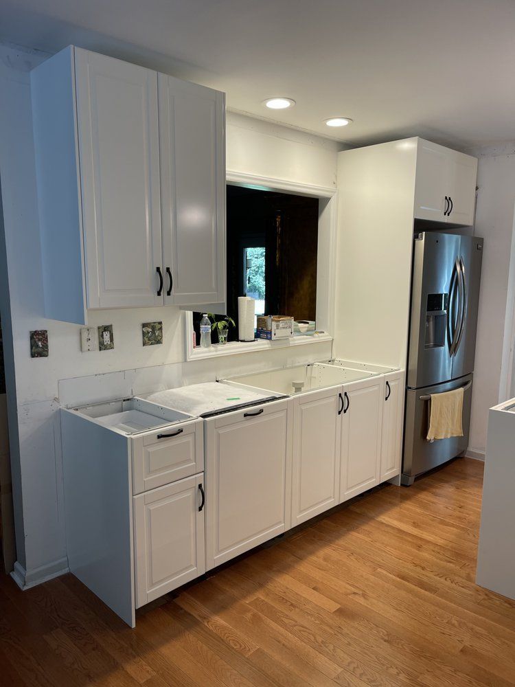A kitchen with white cabinets , stainless steel appliances and hardwood floors.