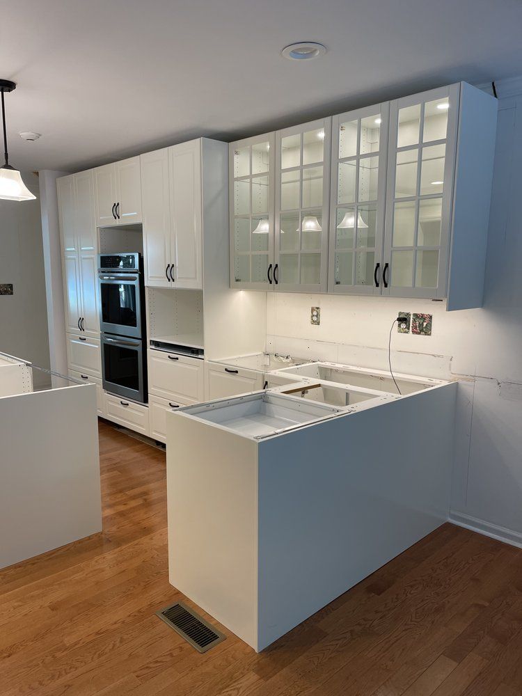 A kitchen with white cabinets , stainless steel appliances , and hardwood floors.
