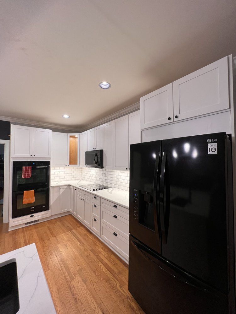 A kitchen with white cabinets and a black refrigerator.