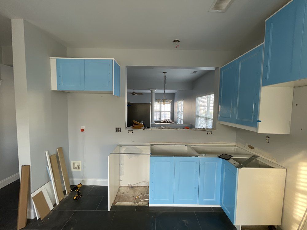 A kitchen with blue cabinets and white counter tops is being remodeled.