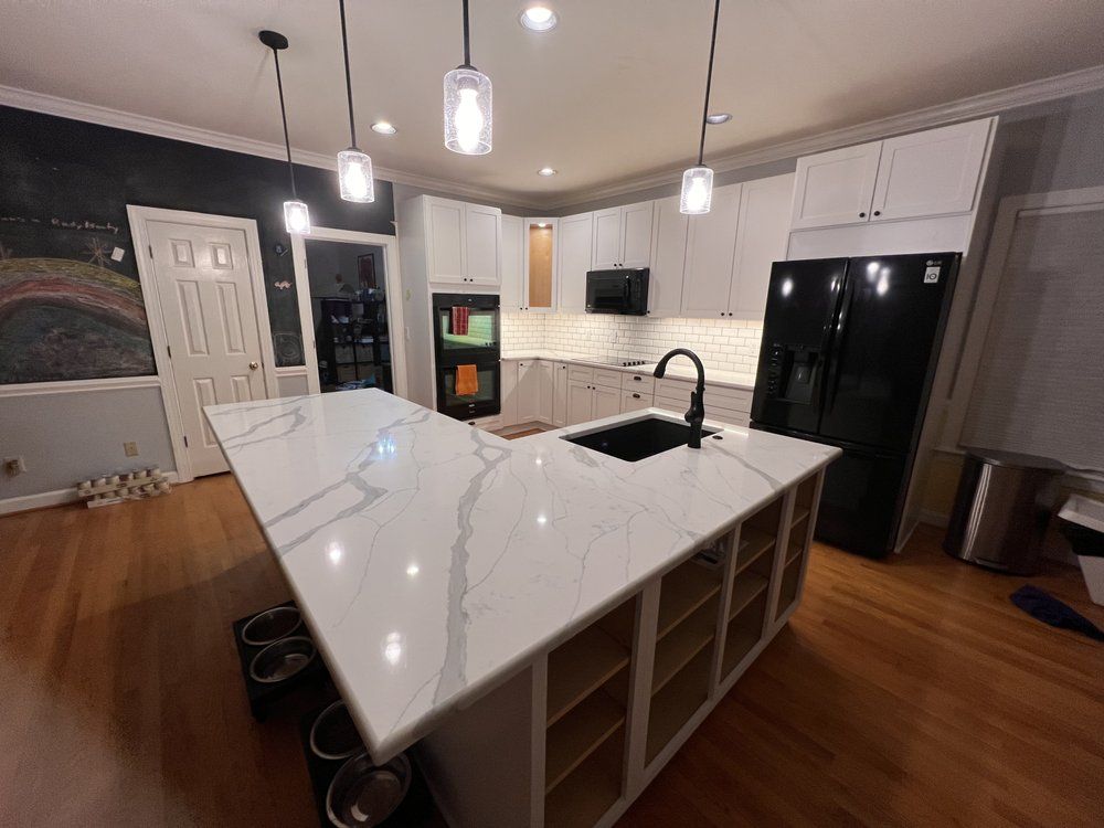 A kitchen with white cabinets and a large island in the middle.