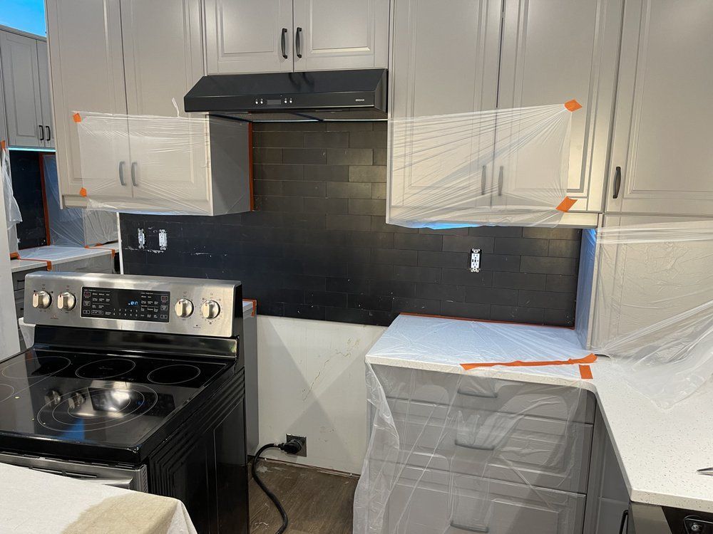 A kitchen with stainless steel appliances and gray cabinets is being remodeled.