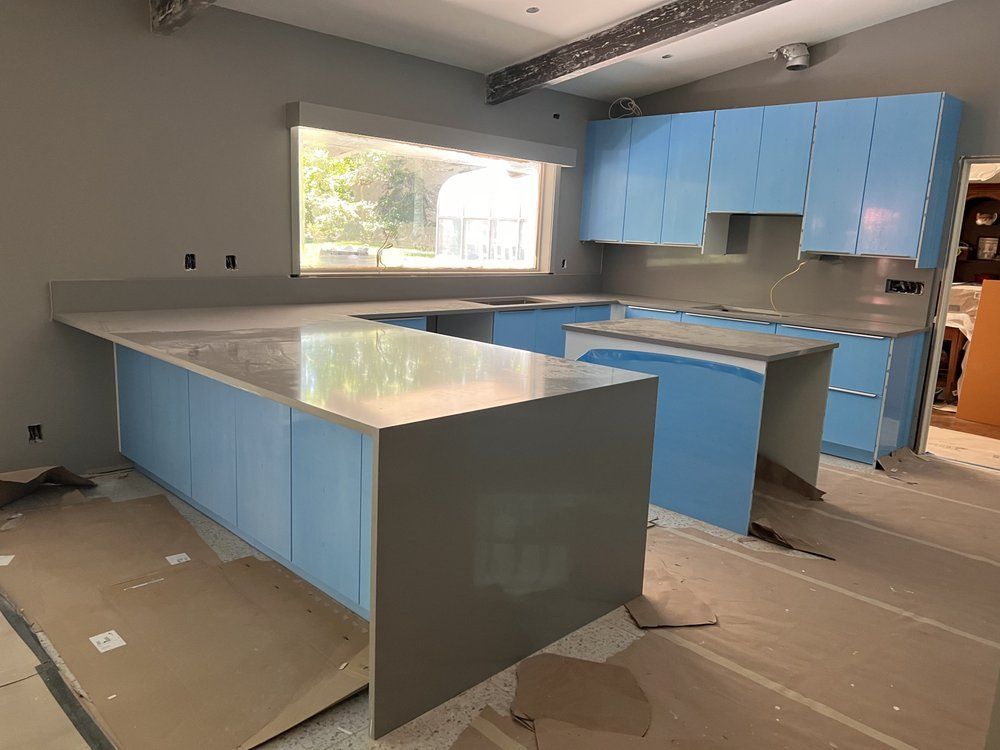A kitchen under construction with blue cabinets and a large island.
