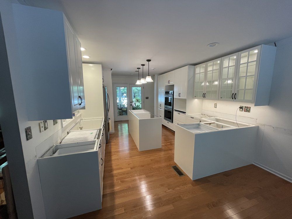 A kitchen with white cabinets and wooden floors is being remodeled.