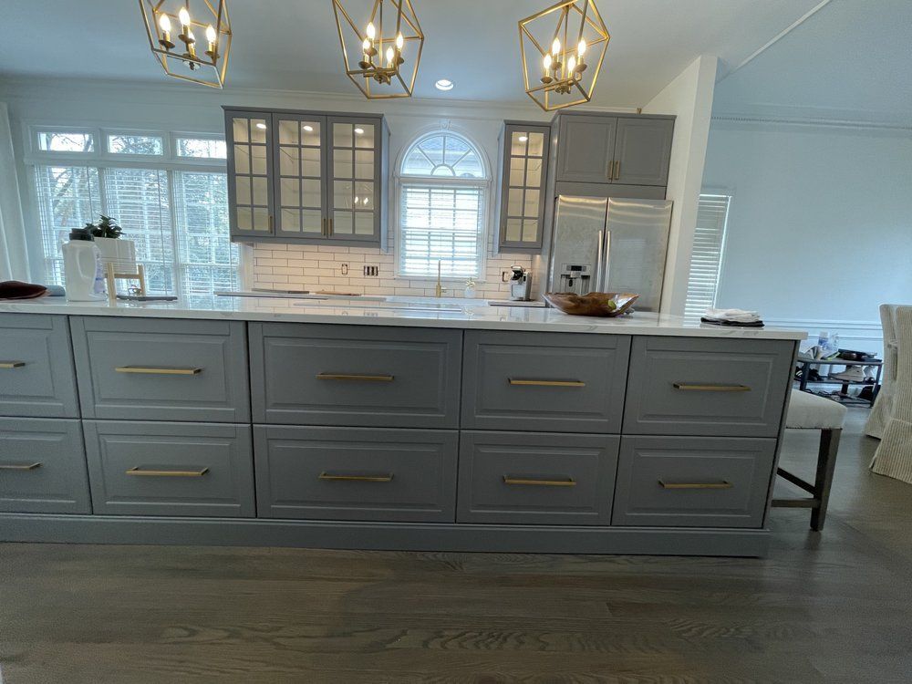 A kitchen with gray cabinets and a large island in the middle.