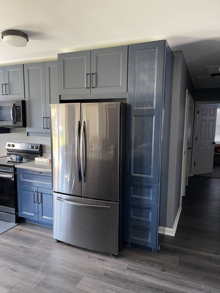 A kitchen with blue cabinets and a stainless steel refrigerator.