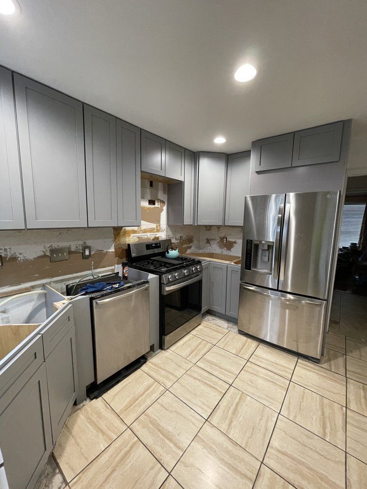 A kitchen with stainless steel appliances and gray cabinets.